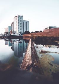 Reflection of buildings in city against clear sky