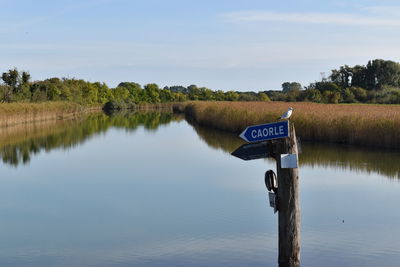 Wooden post in lake against sky