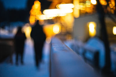 Defocused image of people walking on illuminated street at night