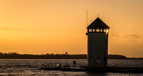 Silhouette of lighthouse at seaside during sunset