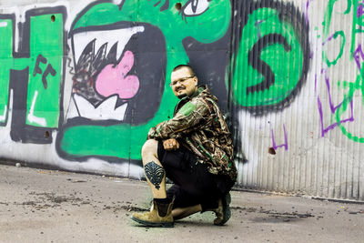 Portrait of smiling young man standing against graffiti wall