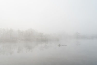 Scenic view of foggy weather against sky during winter