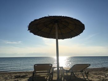 Deck chairs and tables on beach against sky