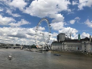 Ferris wheel in city against cloudy sky