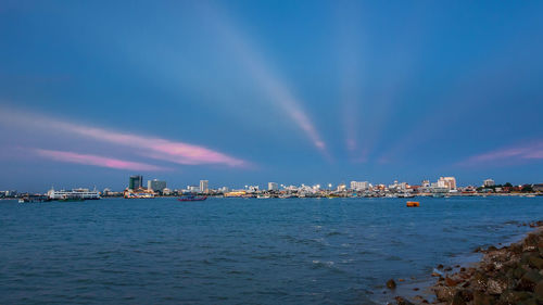 Scenic view of rainbow over sea and buildings against sky