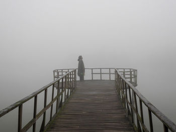 Woman standing on pier against sky during winter