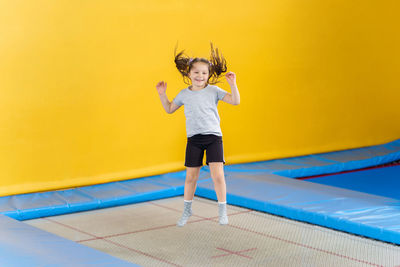 Full length portrait of girl standing on yellow umbrella