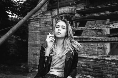 Portrait of young woman standing against building