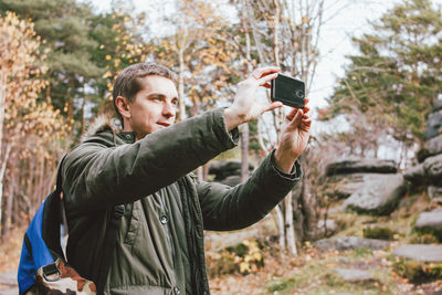 Man photographing by mobile phone while standing in forest