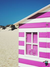 Pink umbrella on beach against clear blue sky