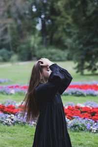 Side view of young woman standing amidst flowering plants