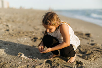 Girl playing on the beach with sand and sea shells barefoot
