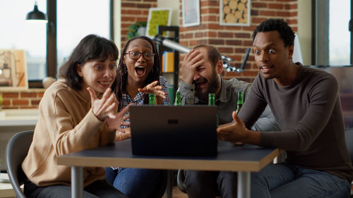 Friends watching laptop at desk in office