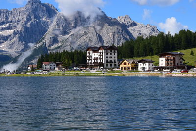 Houses by lake and buildings against sky