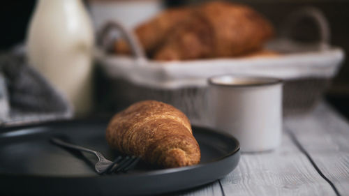 Close up  freshly baked croissant on wooden table with a cup of hot coffee and bottle of milk 