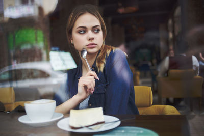 Portrait of a young woman holding ice cream in cafe