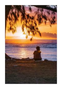 Rear view of silhouette woman sitting on beach