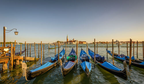 Gondolas moored on grand canal against clear sky