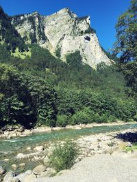 Scenic view of river by mountain against clear sky