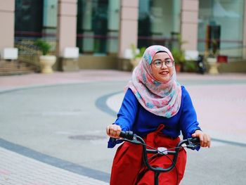 Portrait of smiling young woman on bicycle in city