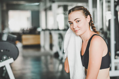 Portrait of smiling young woman wiping face while exercising in gym