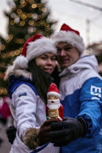 Rear view of women holding christmas tree during winter