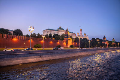 Illuminated buildings in city against clear sky