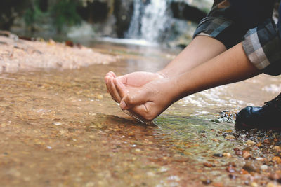 Low section of child cupping water in hands