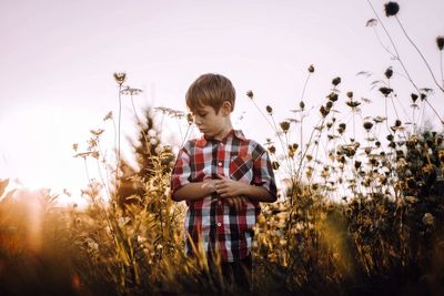 Boy standing on field against clear sky