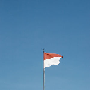 Low angle view of flag against blue sky