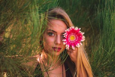 Portrait of beautiful young woman with red flower