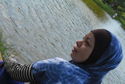 Tilt image of woman in hijab sitting at lakeshore