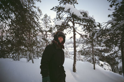 Teenager in fur hat standing in winter scenery