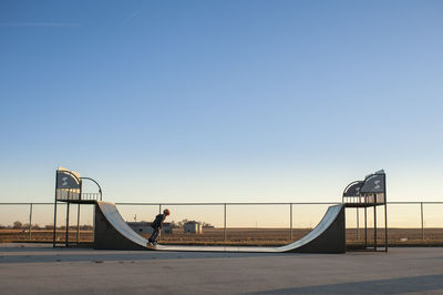 Pullback of young boy riding half pipe at a skate park on sunny day