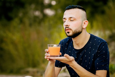 Portrait of young man drinking glass