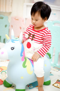 Cute girl holding toy while standing by toys