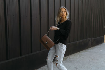 Portrait of young woman standing against wall