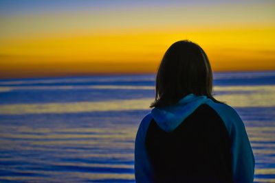 Rear view of woman looking at sea during sunset