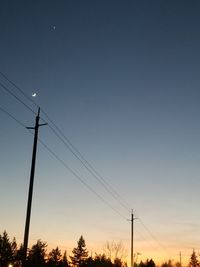 Low angle view of silhouette electricity pylon against sky during sunset