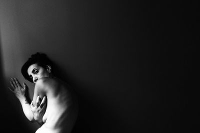 Portrait of young woman against black background