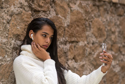 Gorgeous brunette woman with long hair takes self portraits with her smartphone