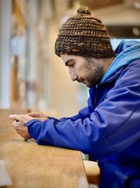 Man holding smart phone while sitting on table