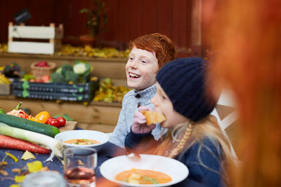 Happy male and female siblings sitting for meal at table