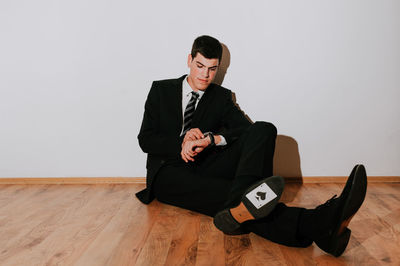 Man with card sitting on floor against wall