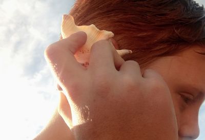 Close-up of boy holding seashell at beach