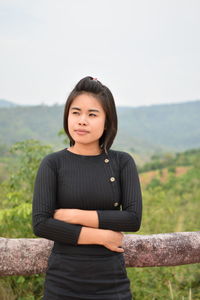 Young woman looking away while standing by railing on observation point against sky