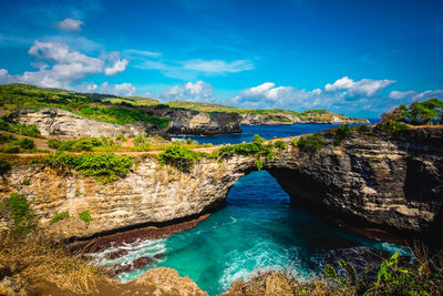 Scenic view of natural pool and cliffs against sky