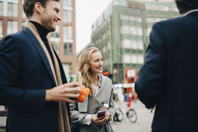 Smiling female entrepreneur with male colleagues in city