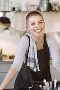 Portrait of happy female owner wearing apron in cafe