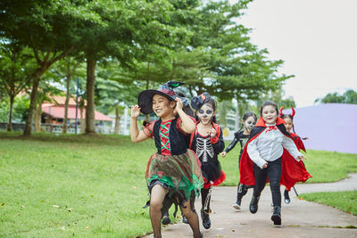 Girls in costumes running on footpath during halloween